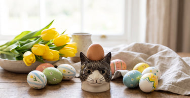Millie katte æggebæger i stentøj fra Quail, stillet op i et stemningsbillede til artiklen Påskebord og pynt: gule farver, æg og forårsblomster