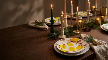 Julebord med citrontallerkener, kertelys i keramikstager, gran og messing