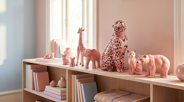 Pink figurer opstillet på en lys flade ved en enkel væg